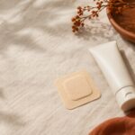 Hormone therapy patch and cream tube on natural linen in warm light