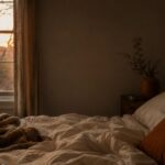 Dark bedroom at dawn with rumpled bedding and soft light through curtains