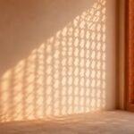 Sunlight through a carved lattice screen falling on a plaster wall