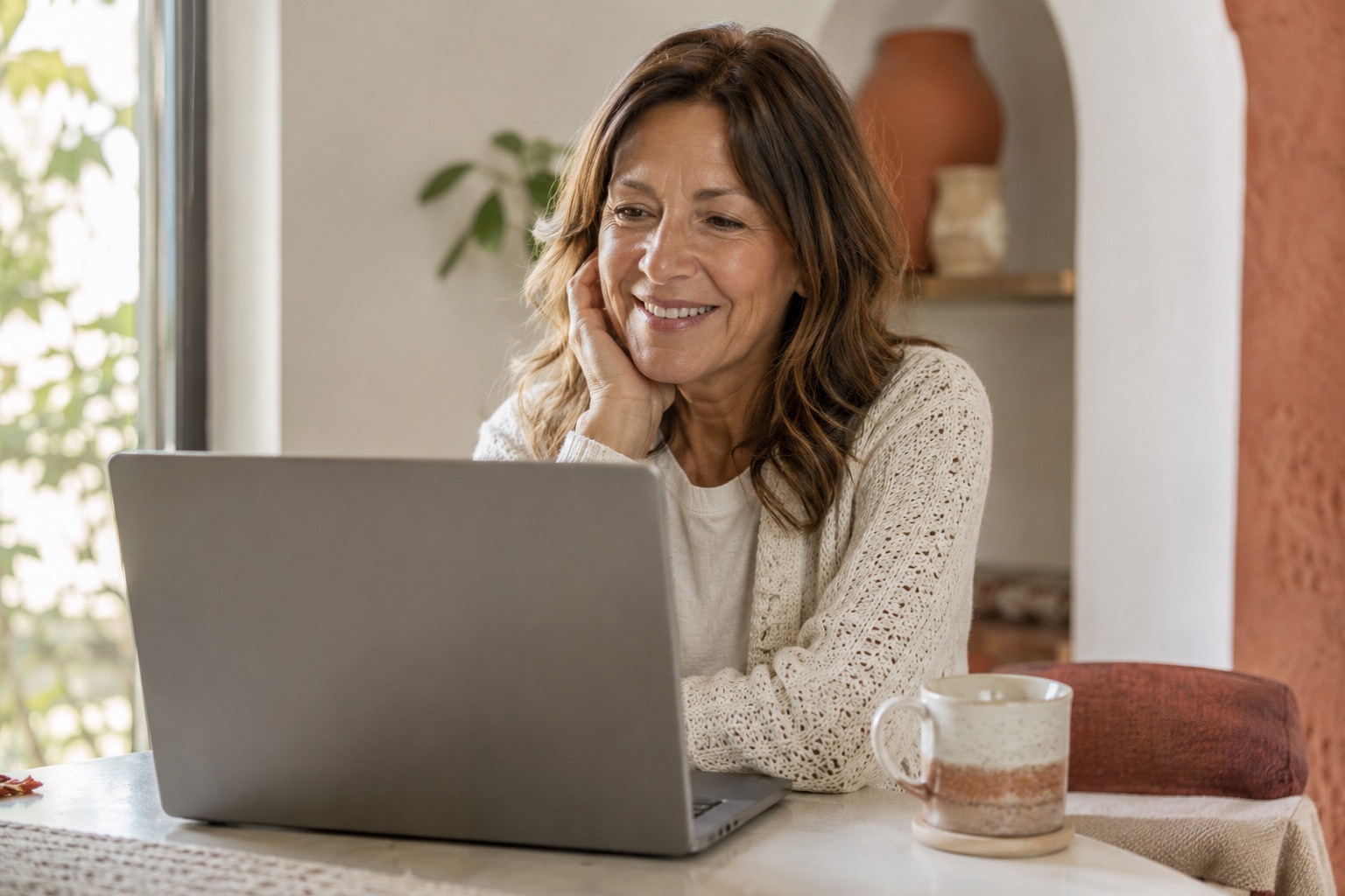 Woman in her fifties on a laptop video consultation with a menopause specialist from home
