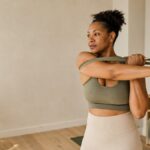 Woman doing a gentle shoulder stretch with a resistance band in a bright room