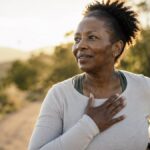 Woman outdoors after a jog resting a hand on her chest to catch her breath