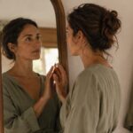 Woman looking thoughtfully at her reflection in a mirror