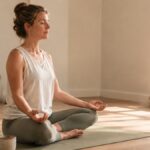 Woman practising slow breathing on a yoga mat by a bright window
